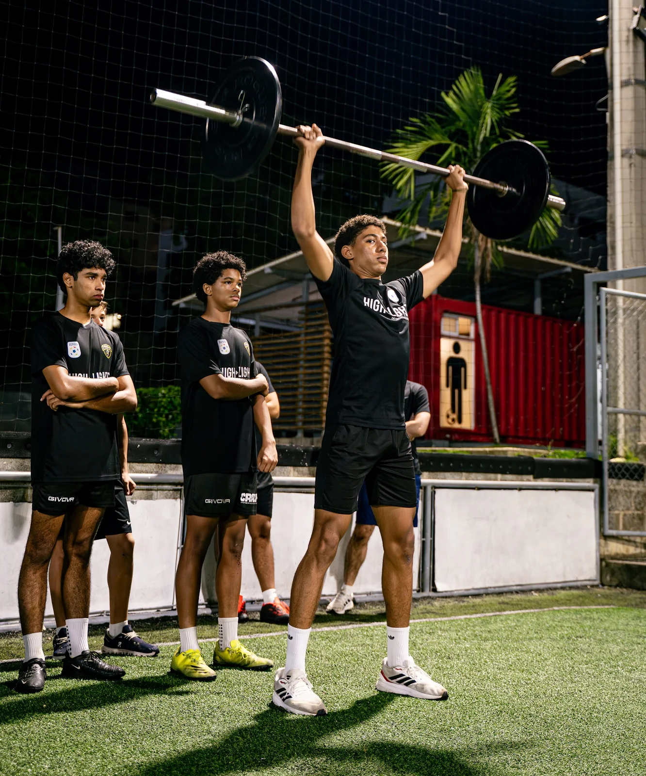 5AM Club athlete lifting a barbell overhead during outdoor training