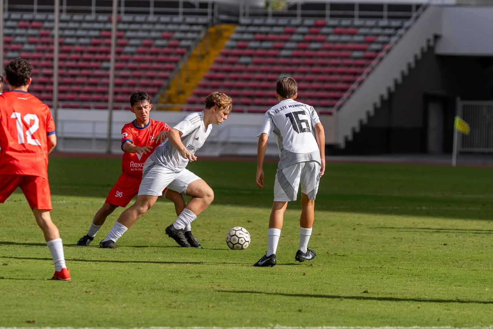Youth soccer players contesting the ball during a stadium match