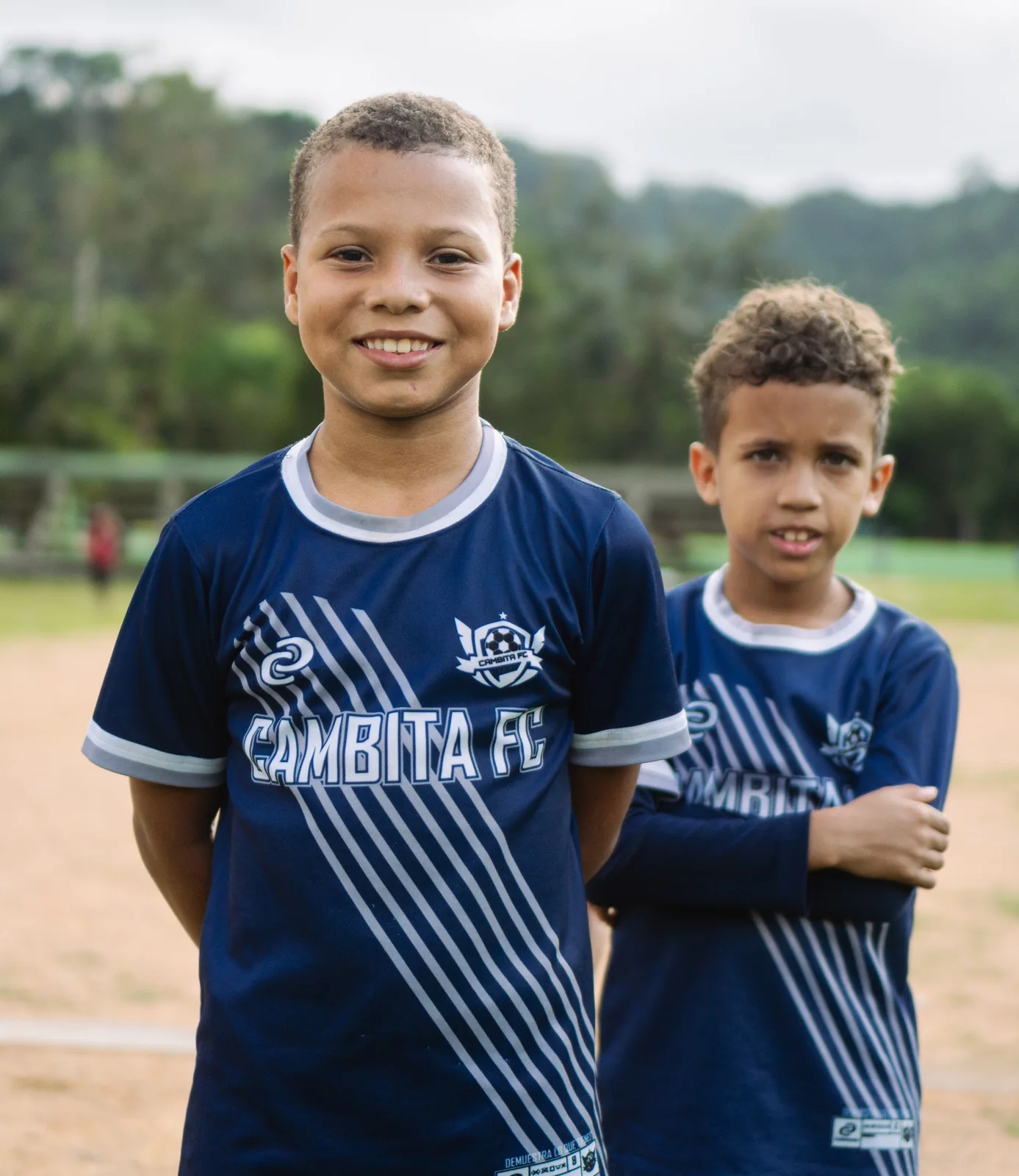 Two children wearing matching soccer clinic shirts on the field