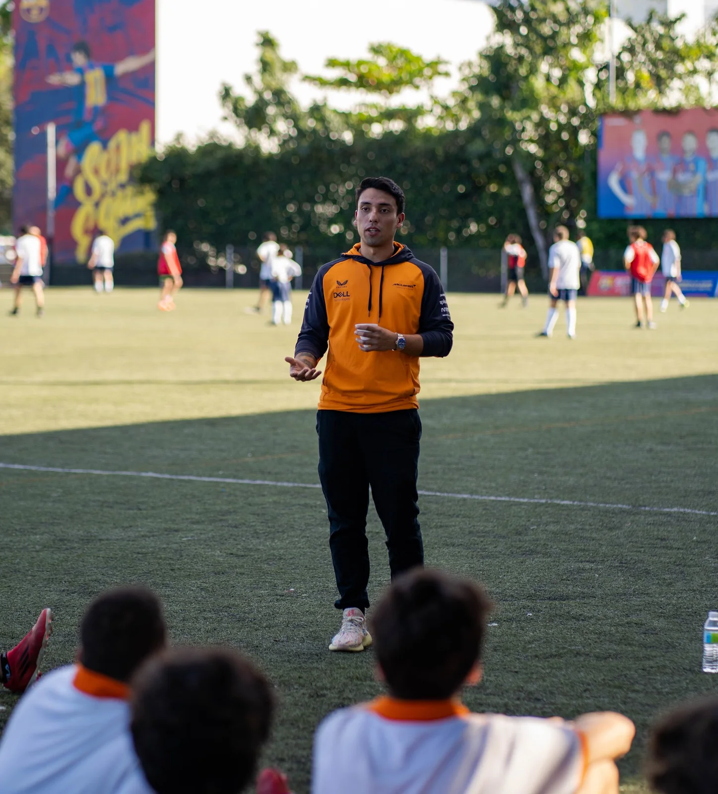 Speaker leading a conversation with athletes beside a soccer field