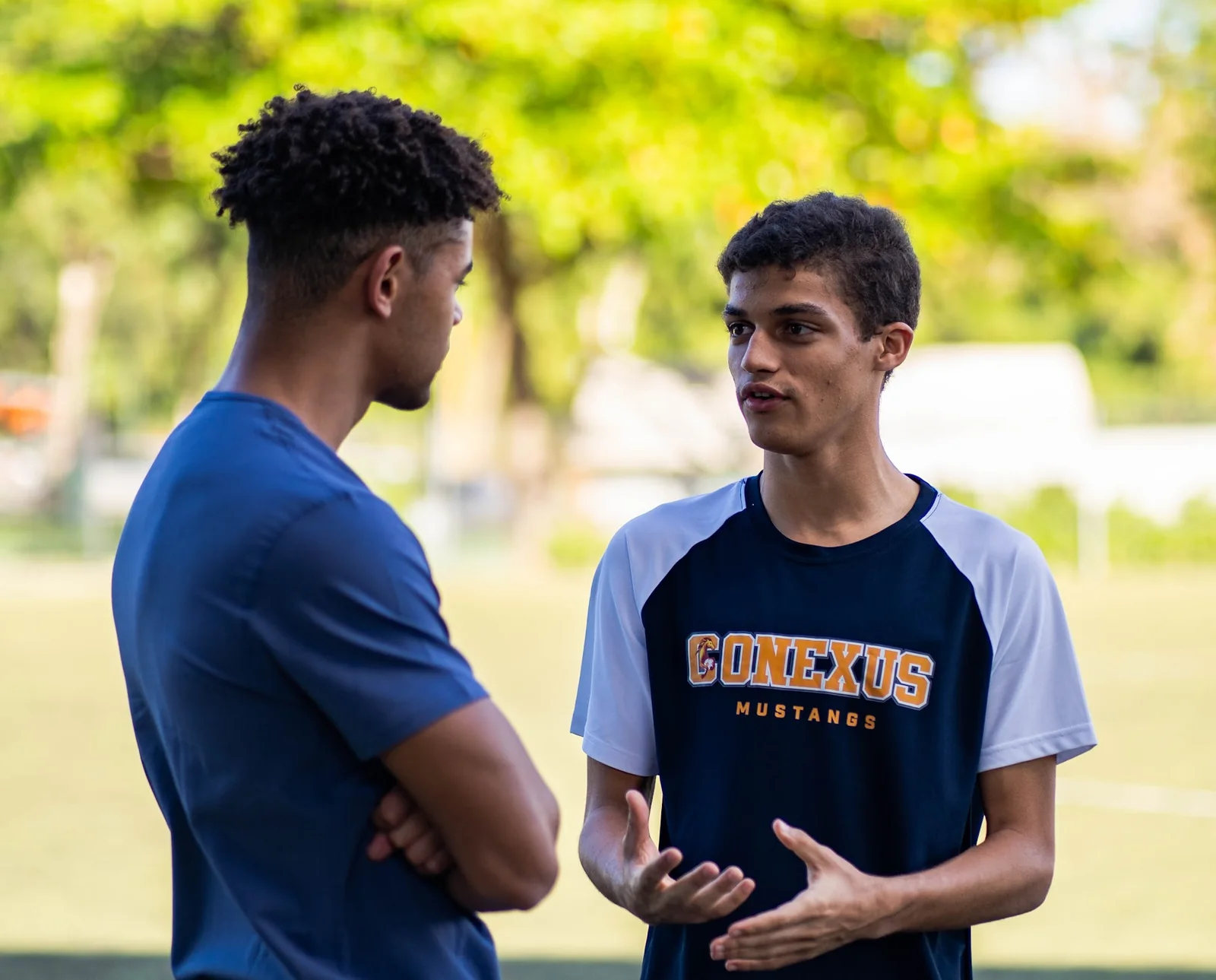 Two athletes in conversation beside a soccer field