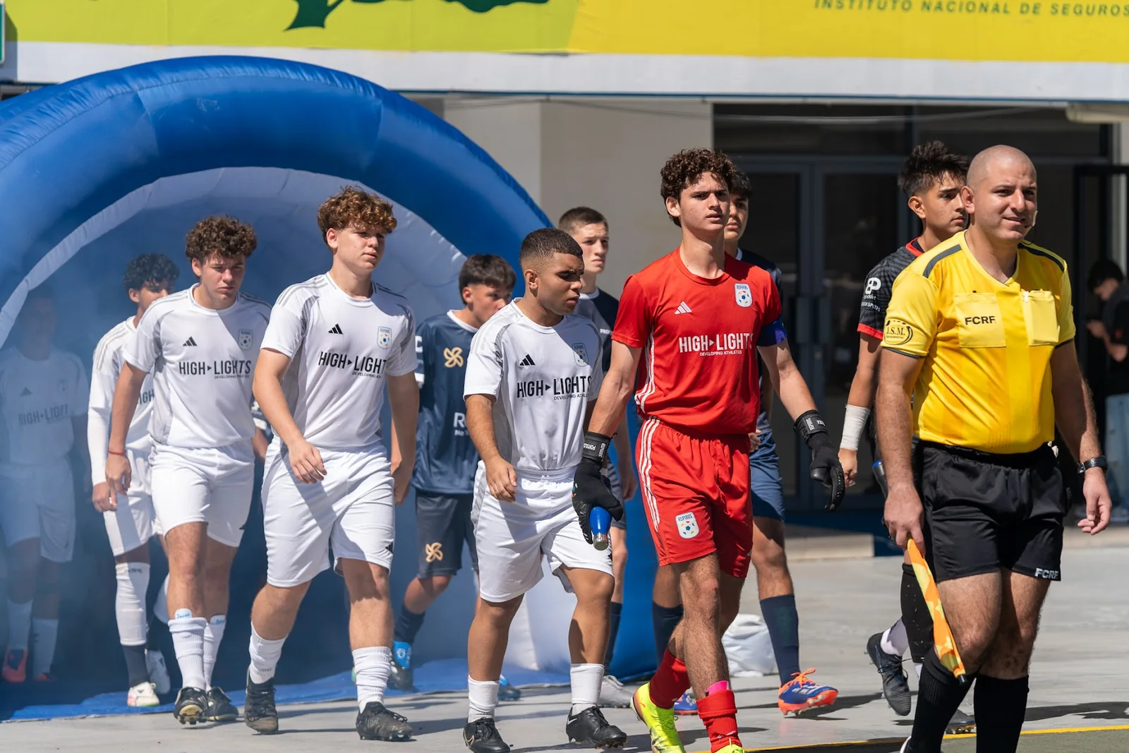 Youth soccer team walking onto the field from a stadium entrance